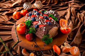 Christmas fruit chocolate cake with berries and fruits with edible Christmas decoration. Close up.