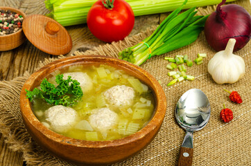 Vegetable soup with meatballs, vegetables on background.