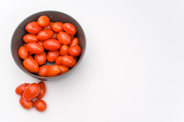 datterini tomatoes in a dark stoneware bowl on a white background