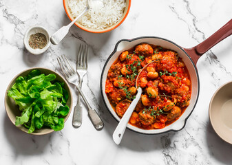 Delicious lunch - roasted meatballs with beans in tomato sauce, rice and green salad on a light background, top view