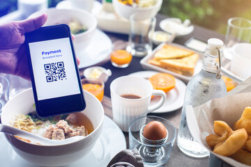 Hand using smart phone to scan QR code on tag with blurry food, dessert and customers in coffee shop to accepted generate digital pay without money. Qr code payment concept.