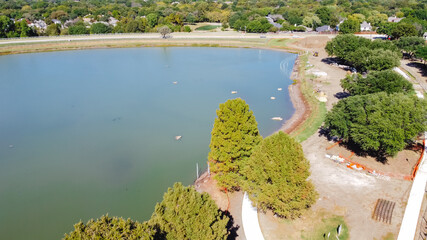 Top view residential pond renovation with construction machines and safety barrier fence at Rheudasil Park, Flower Mound, TX