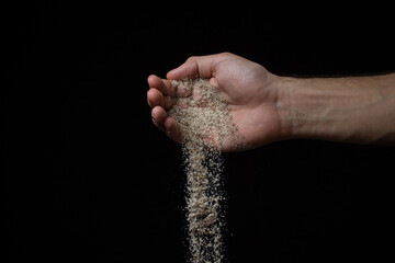 Salt mixed with spices on a black background. A mixture of salt and spices is poured out of a man's...