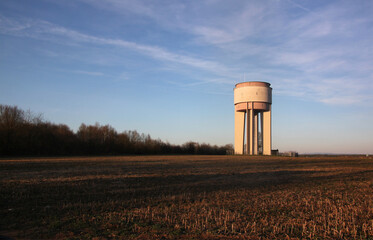 Modern cylindrical concrete water tower on a harvested grain field near Ramstein-Miesenbach village...