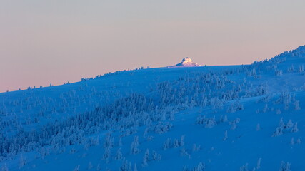 Winter snowed up mountain ridge at sunrise.