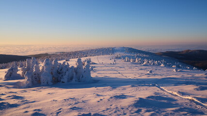 Hiking route on snowed up mountain ridge in winter at sunrise light