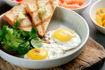 Traditional breakfast in the morning with fried eggs, green salad and toast on a plate. Healthy and nutritious breakfast in the morning, close up