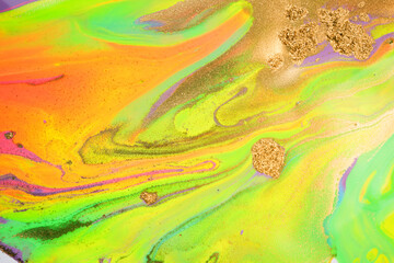 Mixture of acrylic bright paints with yellow gold glitter. Marble imitation background.