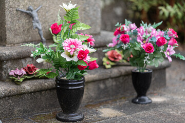 Potted plastic flowers in front of a gravestone
