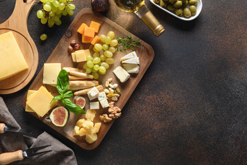 Cheese platter with grapes, nuts, figs on brown background. Top view. Copy space.