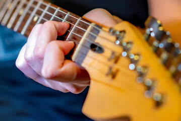 Male fingers in soft focus play chords on the strings of an electric guitar. Guitar education  at a music school.Performance, concert of guitar music.