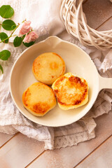 Cottage cheese pancakes, syrniki, curd fritters. Syrniki in small white pan. Top view. Homemade food