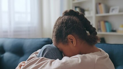 Upset child sitting on the sofa, waiting for parents, thinking of school trouble
