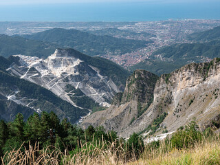 View of the marble Quarries of Carrara, the paths carved into the side of the mountain and the town of Carrara and the Coast in front of it