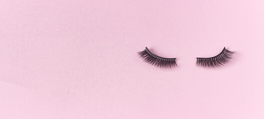 Artificial eyelashes on a pink background, free space for text. The concept of eyelash extensions, makeup.