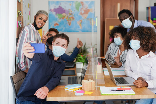 Multiracial coworking people staff taking a selfie while wearing safety face mask for coronavirus outbreak