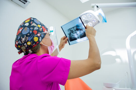 female dentist looking at an X-ray against a spotlight