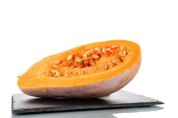 One half of ripe organic pumpkin on a slate stone, close-up, isolated on white.