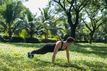 Sporty active young man in black sportswear doing sport exercises in the park. Fit caucasian man...