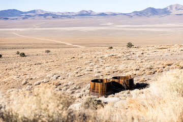 Two wooden water cisterns at the top of a big valley with mountains beyond