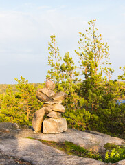 Pyramid made by stones. Stone tower and forest in the background. Rocks on the pine forest. Stone pile was made by tourist. Beautiful landscape. Concept of balance, harmony and vacation.