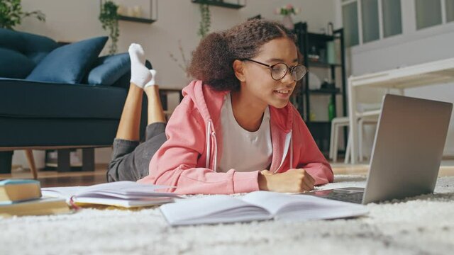Schoolgirl talking to friend online by video chat at home, distance learning