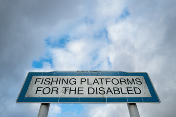 Weathered Disabled Fishing Platform sign seen located a nearby area within a fresh water river....