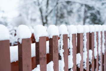 Snow cover. Winter weather. Garden under snow. Close-up of wooden fence covered in snow during...