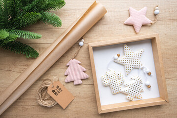Gift box with Christmas toys made of white fabric gold dotted, roll of kraft paper, fir branch on a wooden background. Eco packaging concept, zero waste. Gift wrapping for the holidays, New Year.