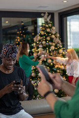 holidays, celebration and people concept - happy friends showing smartphone at home Christmas party