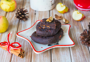 Lithuanian dessert, sweet apple fruit candy in the form of heads of cheese with spices on a white plate a star on a light wooden background. Christmas sweets.