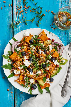 vegetable salad made with sweet potatoe, rocket, red onion, bilberries, feta cheese