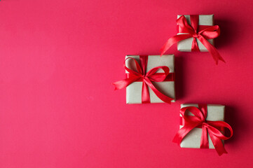 Festive concept - gifts with craft paper with a red bow on a red background. composition for christmas, new year and holidays. flat lay with place for text.
