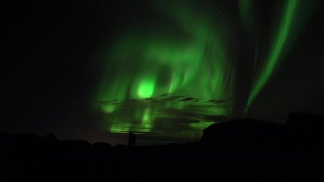 An embracing couple watches aurora borealis real-time video