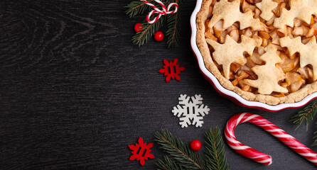 Apple pie with Christmas decoration (Christmas tree cookies), black bakground, copy space, top view.