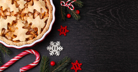 Apple pie with Christmas decoration (Christmas tree cookies), black bakground, copy space, top view.