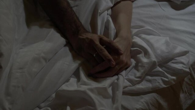 Male and female hand on the bed. Young married couple sleeping on the bed, hands close-up. Love and happy family concept