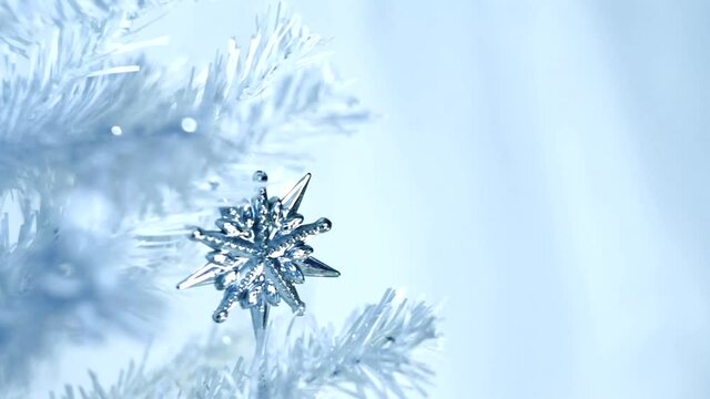 The star of Bethlehem sparkles on a white Christmas tree on a blue background, sparkling sparkles are flying. Christmas star glitters on a white spruce branch. New Year Christmas. Background video, co