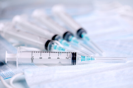 Five medical syringes are on the table. Disposable syringes and medical masks. Consumables for injection and virus protection.