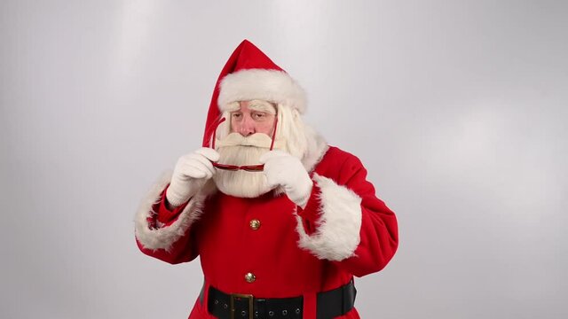 Santa claus puts on sunglasses and starts dancing on a white background.