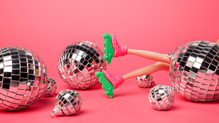 Creative Christmas layout made with disco balls and doll legs with rollerblades on vibrant pink background. Minimal Xmas or New Year celebration concept. Party festive composition.