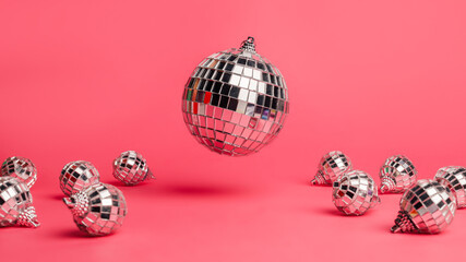 Creative Christmas layout made with flying and levitating disco balls with small silver balls on vibrant pink background. Minimal Xmas or New Year celebration concept. Party festive composition.	