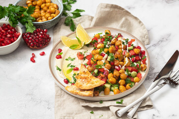 Vegetable salad with chickpeas, tahini sauce and pomegranate