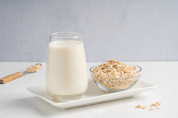 Vegan homemade oat milk with creamy oatmeal taste, lactose and dairy free served in drinking glass...
