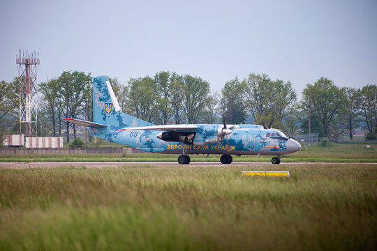 UKRAINE, KYIV, - MAY 28, 2021: AN-26 of the Ukrainian Armed Forces plane on the airport runway. Aircraft flying. Evening dark storm clouds. Dramatic sky. Aiport apron and terminal.