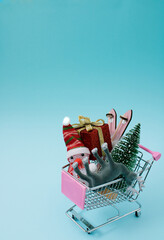 Christmas scene, creative shoping cart, trolley with winter accessories snowman, raindeer, christmas tree, skis with lights on background.  New year and xmas decoration concept with copy space. 