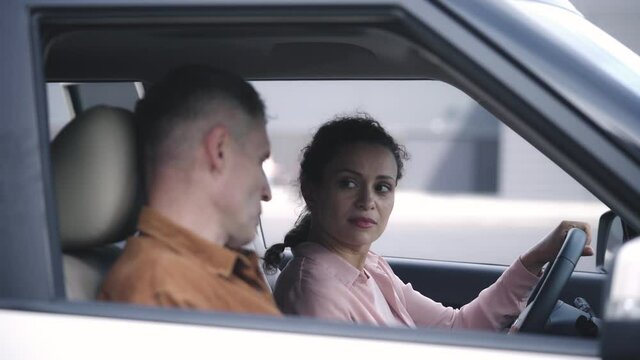 Male instructor helping female newbie driver to start engine, driving lessons