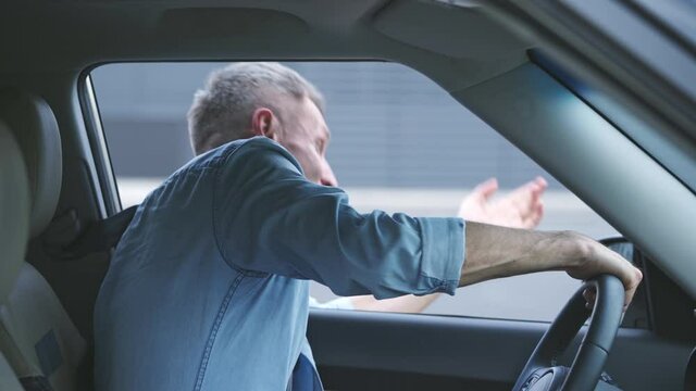 Annoyed male driver yelling out of car window, conflict, risk of road accident