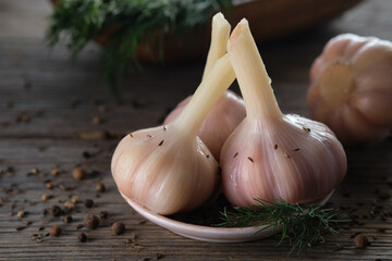 A few heads of pickled garlic. Salted garlic in a plate on kitchen table.