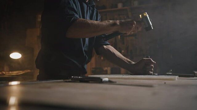 Unrecognizable craftsman working with skin material on workplace table at workshop